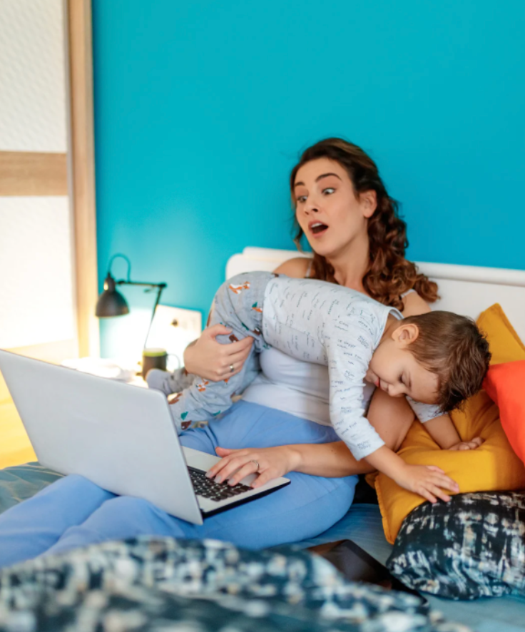 Mom trying to work on laptop with toddler jumping on her – overwhelmed parent trying to balance work and family while experiencing parenting stress
